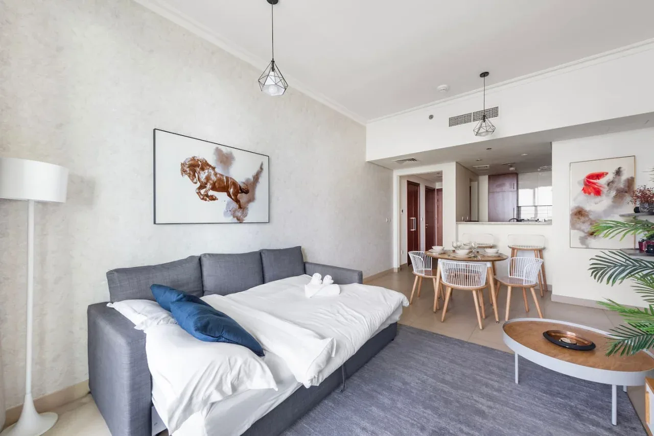 Una sala luminosa con un sofá seccional gris y un comedor.