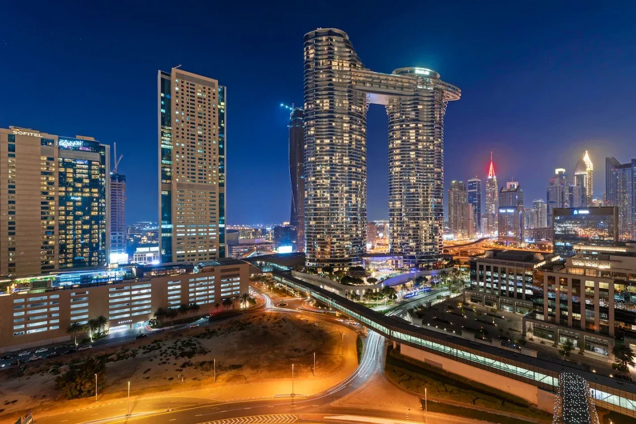 Un horizonte urbano nocturno con edificios altos iluminados y carreteras.