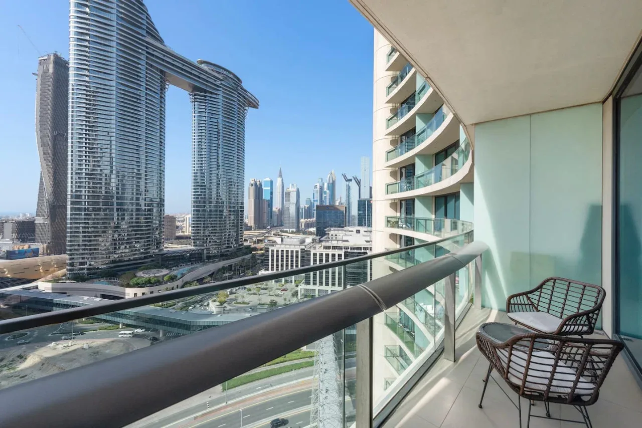Un balcón da a un horizonte urbano moderno, con asientos junto a la barandilla de cristal.