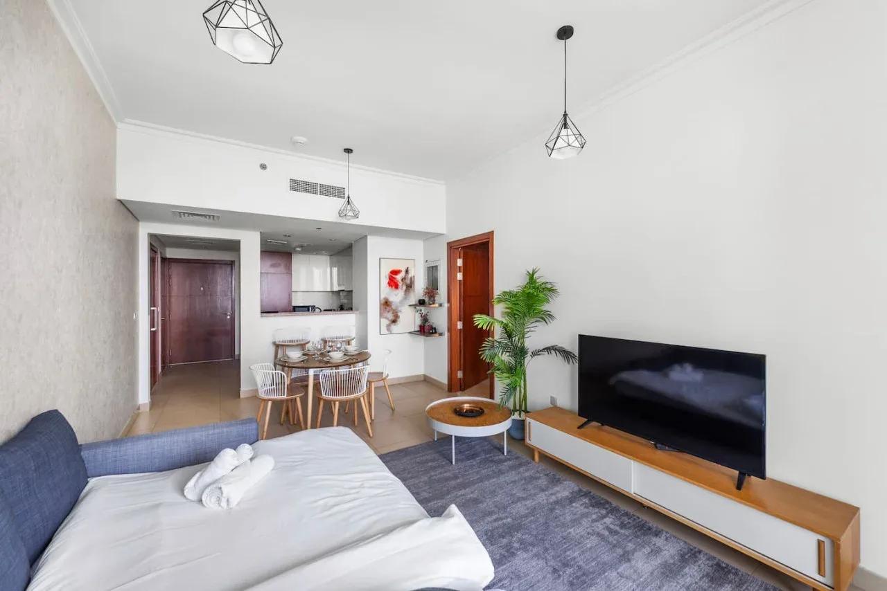 Una sala luminosa con una cama, un televisor y un comedor.