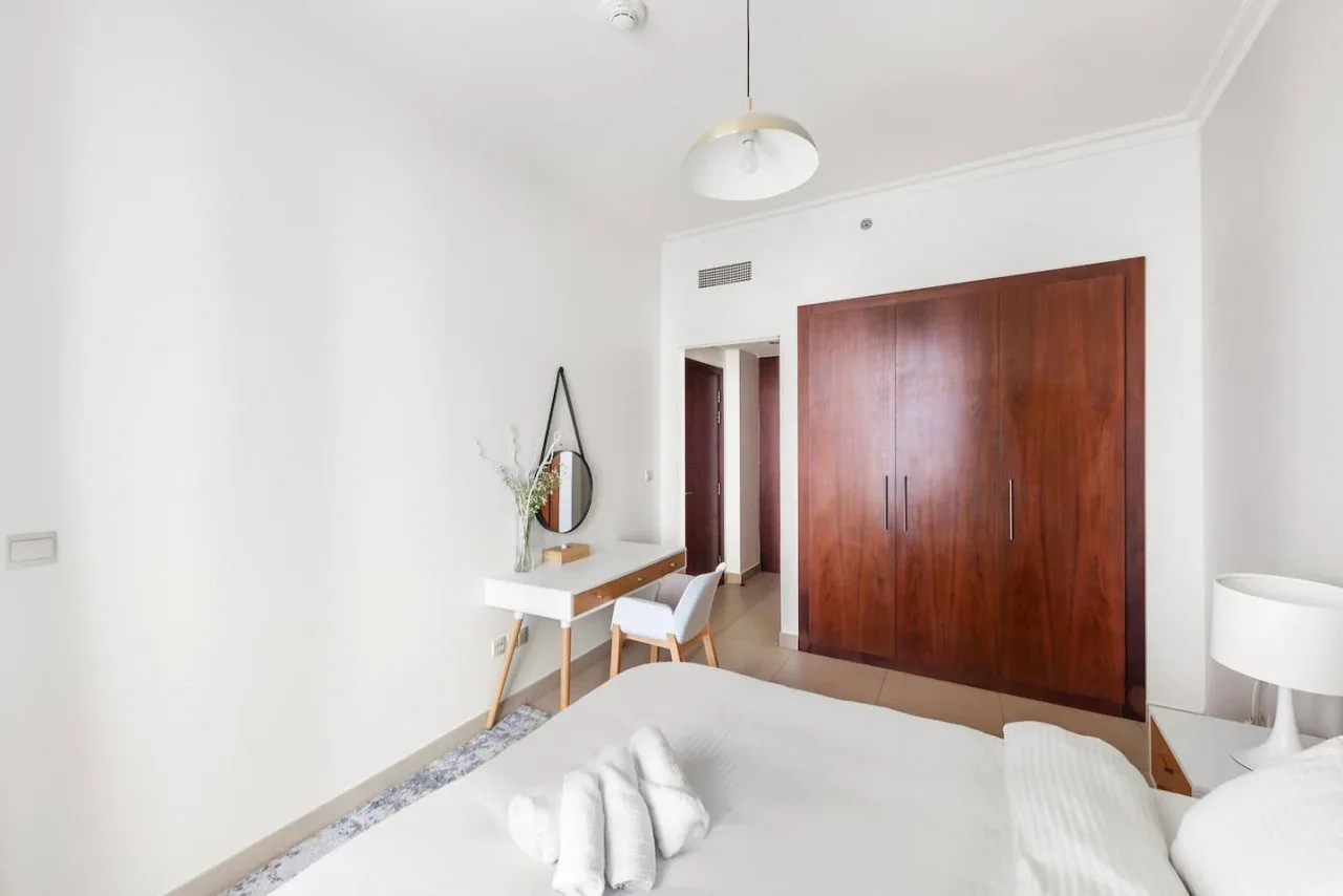 Un dormitorio luminoso con un gran armario de madera y un escritorio pequeño.