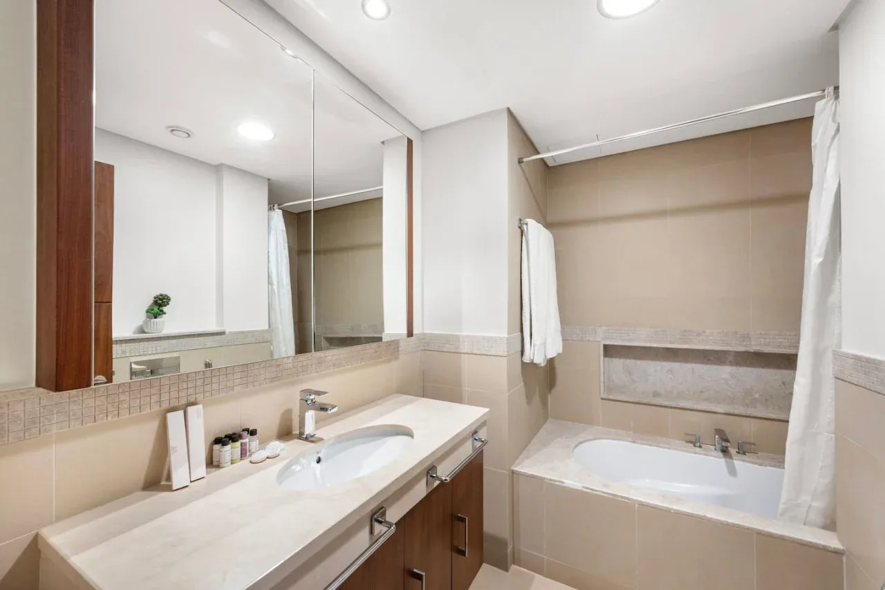 Un baño con un tocador largo, espejo y bañera.