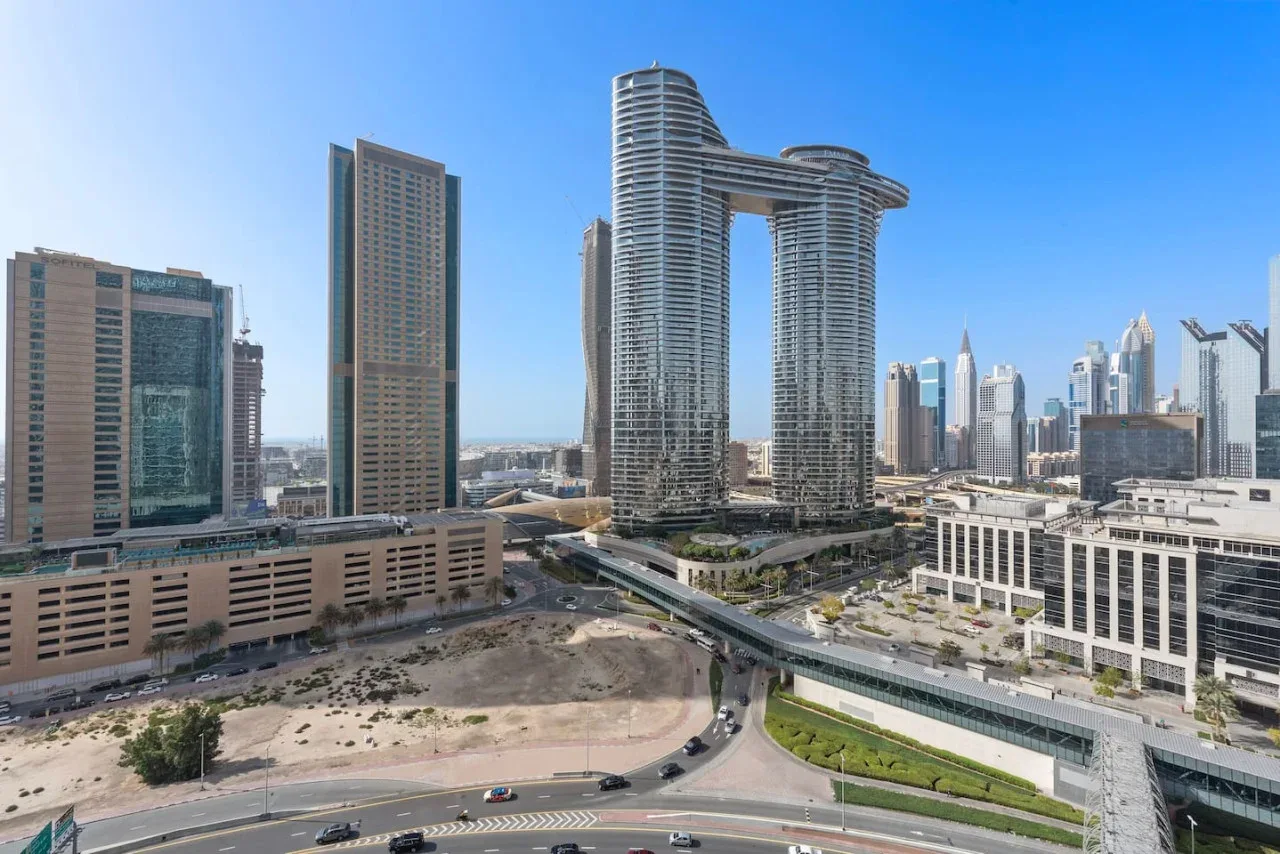 Un horizonte urbano con edificios modernos altos y una vía elevada curva.