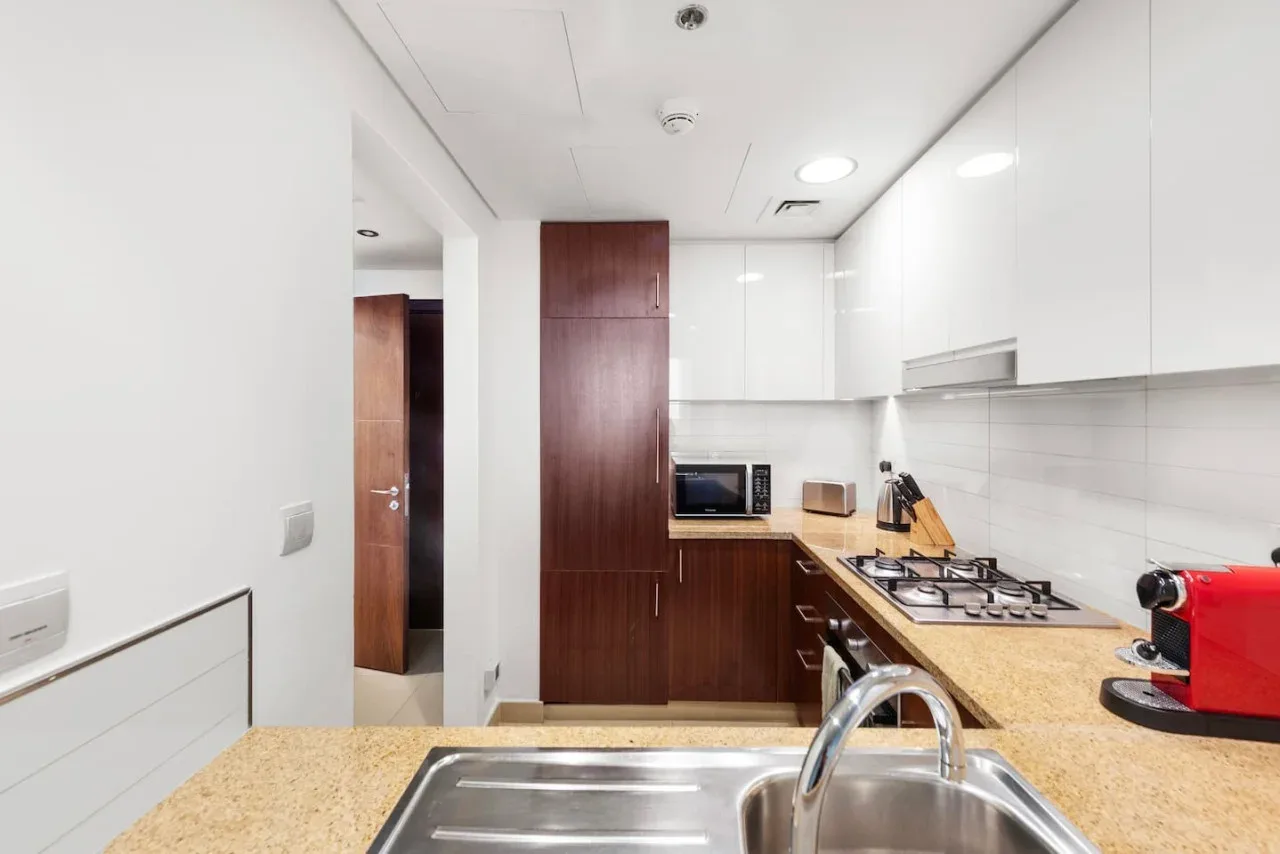 Una cocina moderna con armarios de madera oscura, una encimera y un fregadero de acero inoxidable.