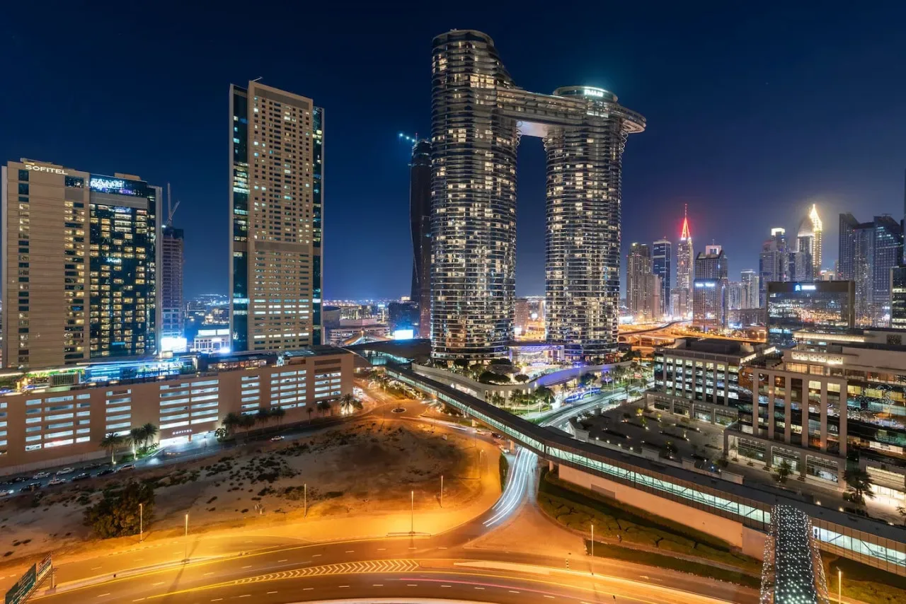 Un horizonte urbano nocturno con edificios altos iluminados y carreteras.