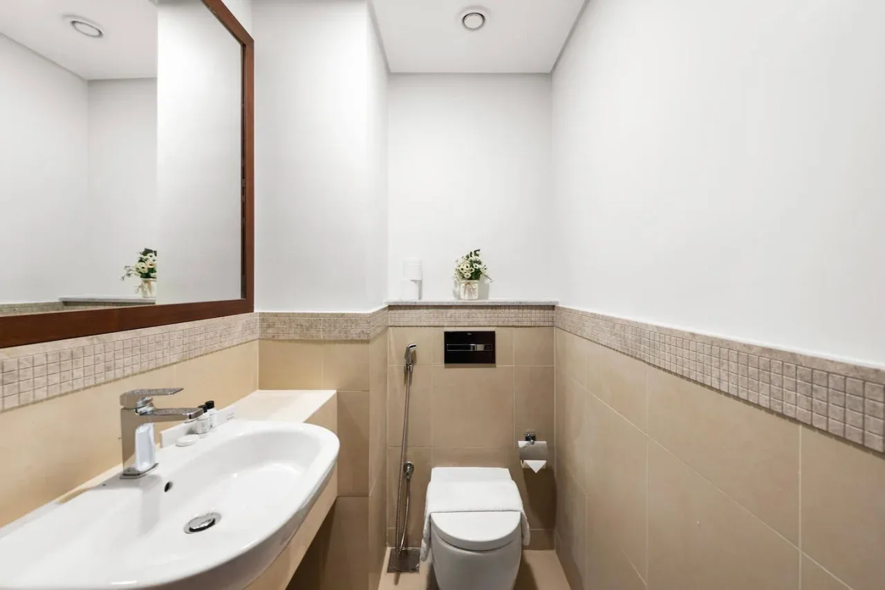 Un baño con lavabo, espejo e inodoro.