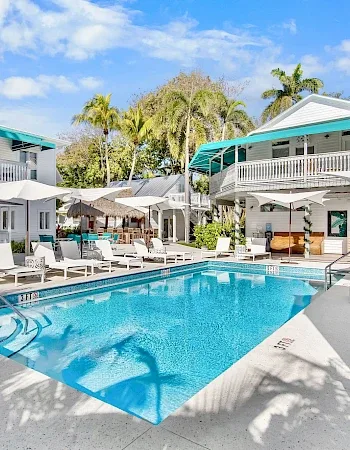 Hotel courtyard pool with poolside chairs, umbrellas, and surrounding buildings