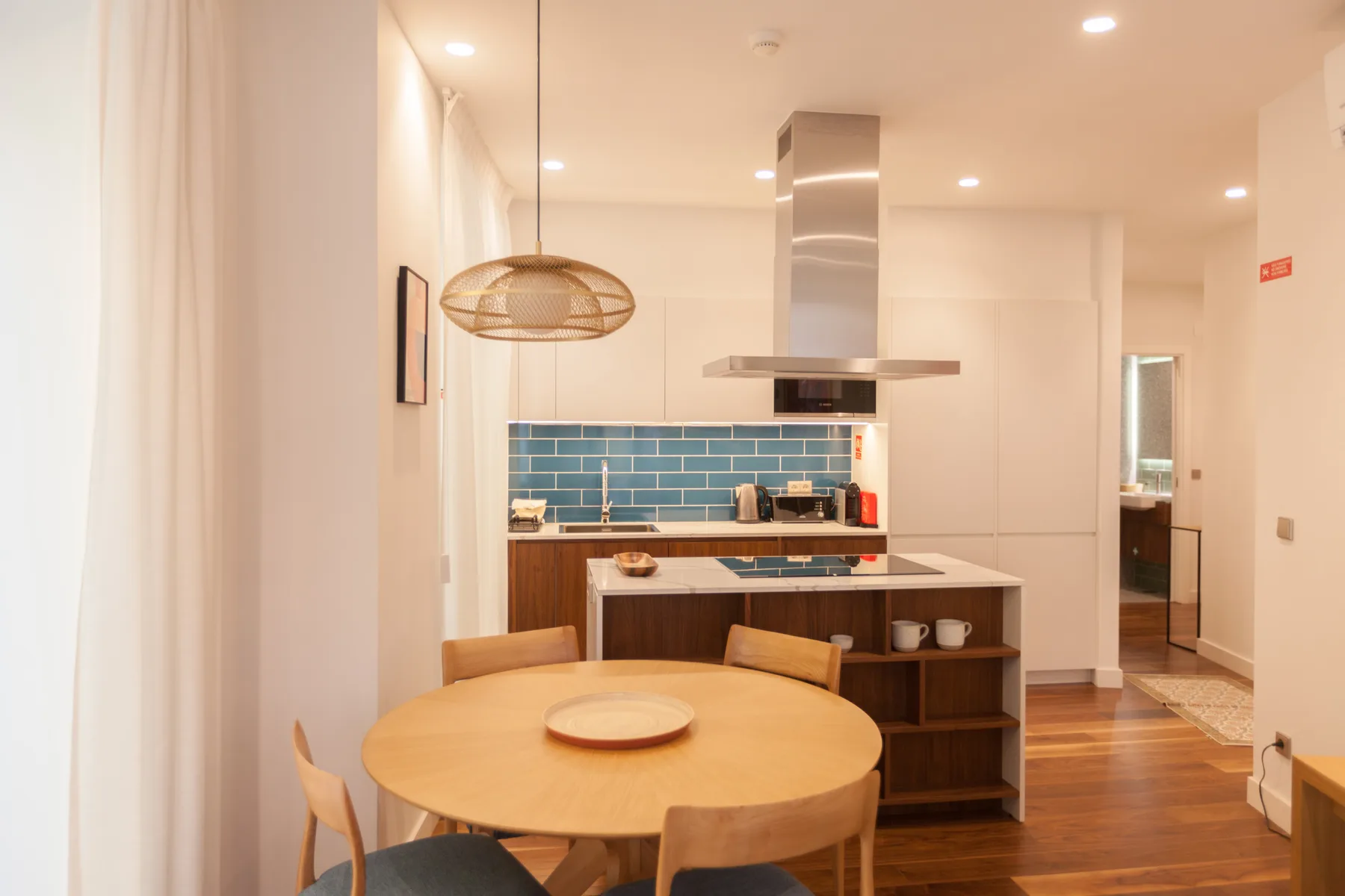 An open-plan kitchen and dining area with a round wooden table.