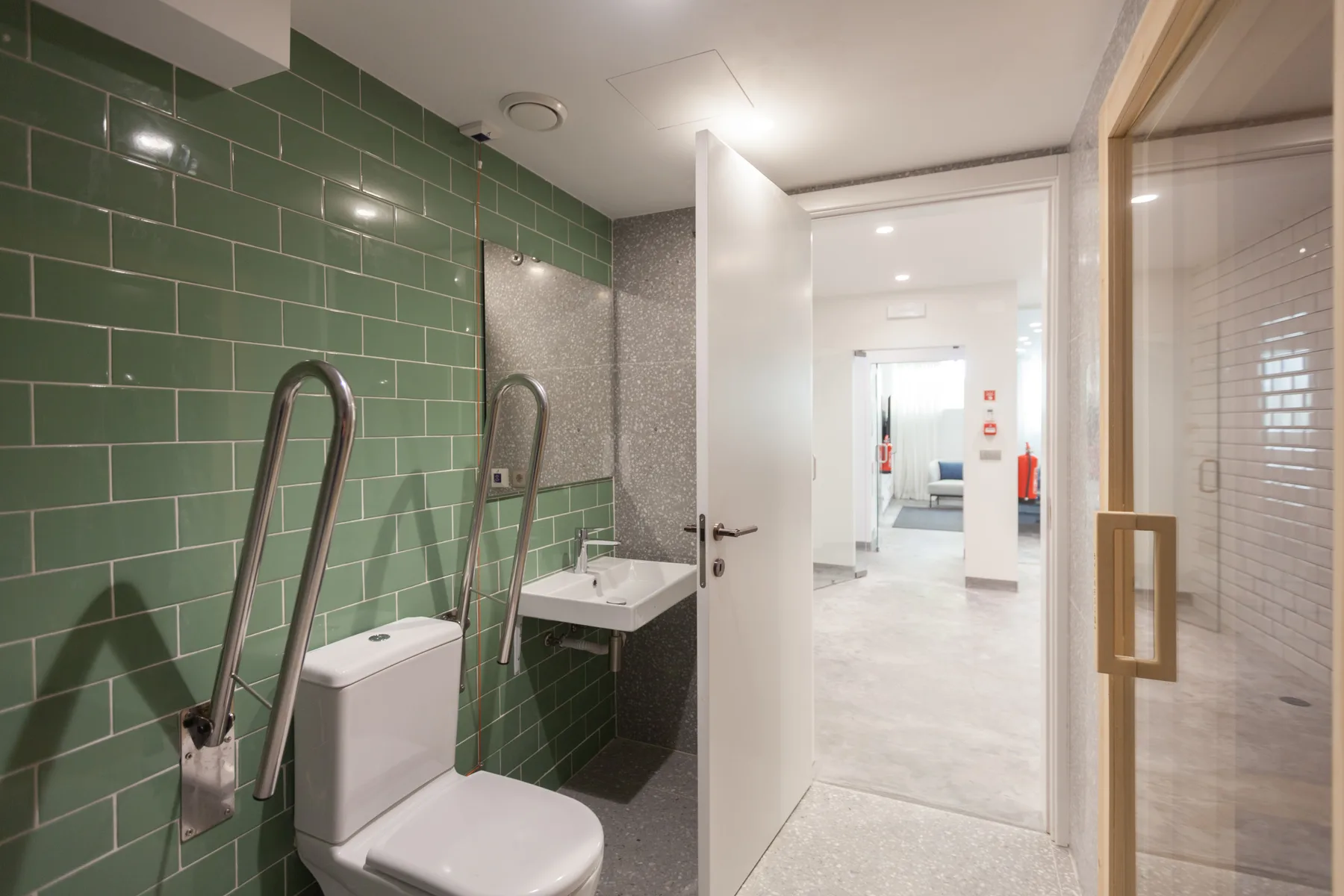 A tiled bathroom with a toilet, sink, and open doorway.