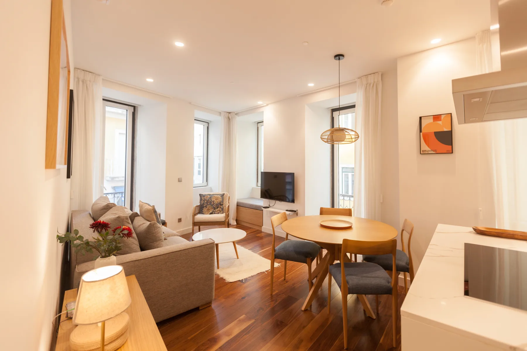 A bright living and dining room with seating around a wooden table.