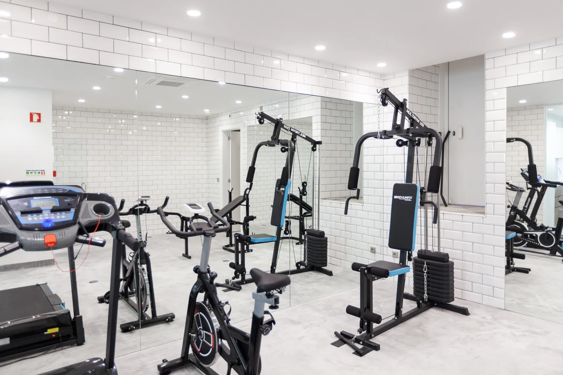 A gym with exercise machines and mirrored walls.