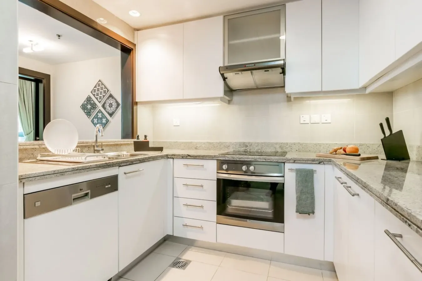 A bright kitchen with white cabinets, stone countertops, and a built-in oven.