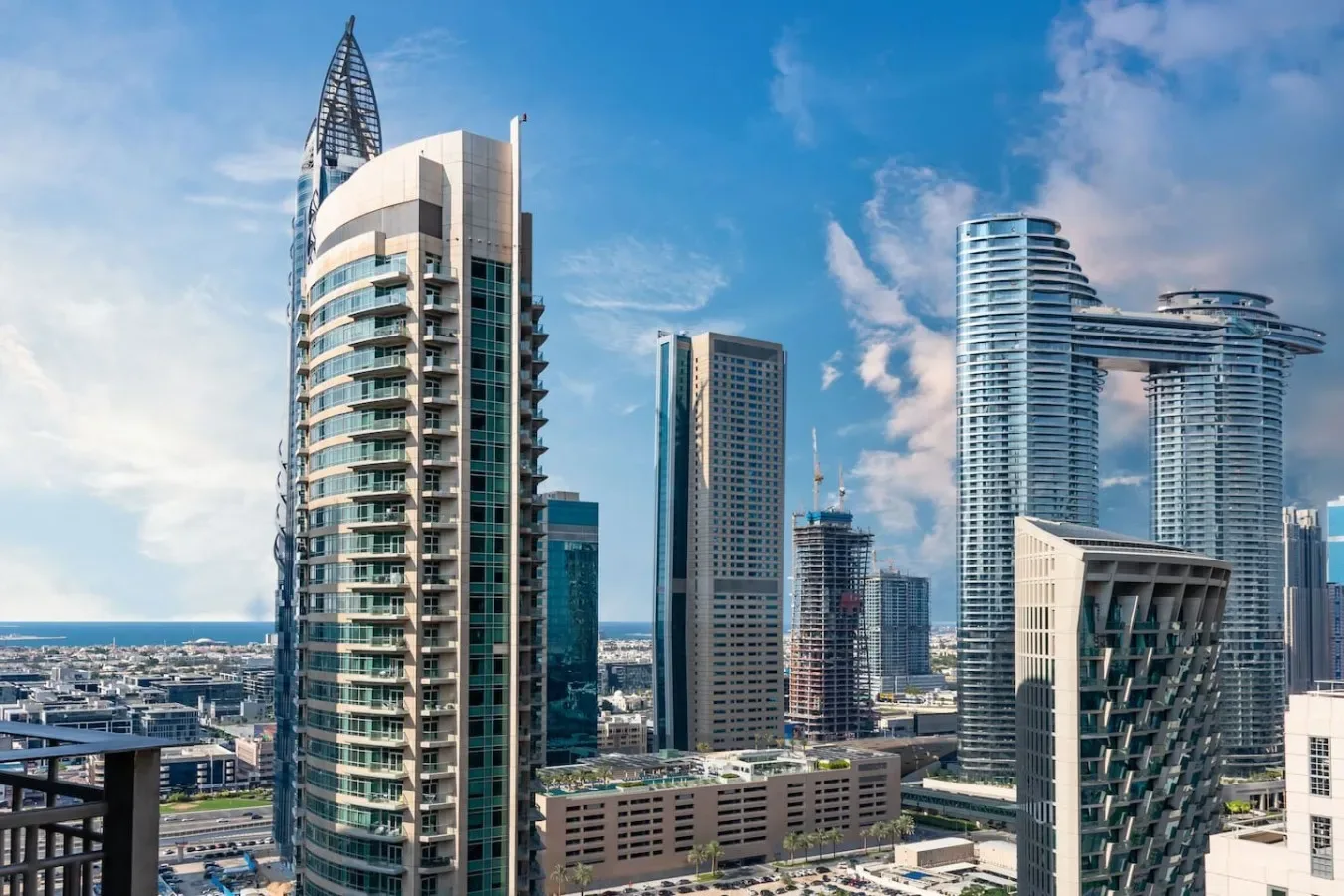 Modern high-rise buildings stand against a blue sky in a city skyline.