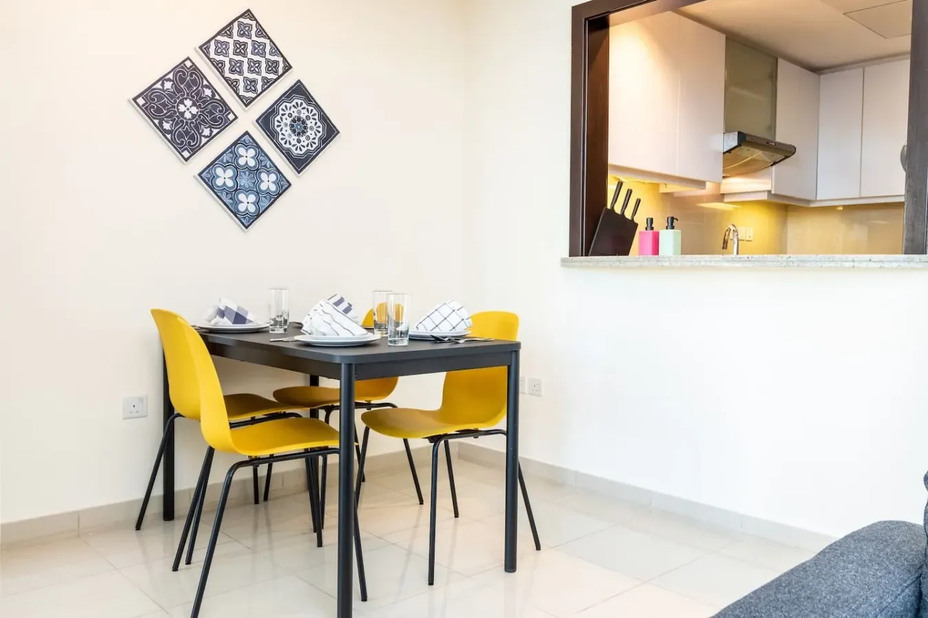 A dining area with a table and yellow seating beside an open kitchen.