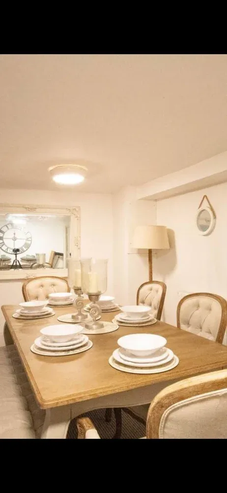 A dining area with a wooden table set with plates and glassware.