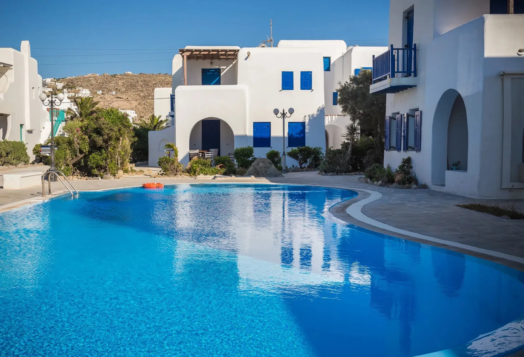 Una piscina está rodeada de edificios blancos bajo un cielo azul despejado.