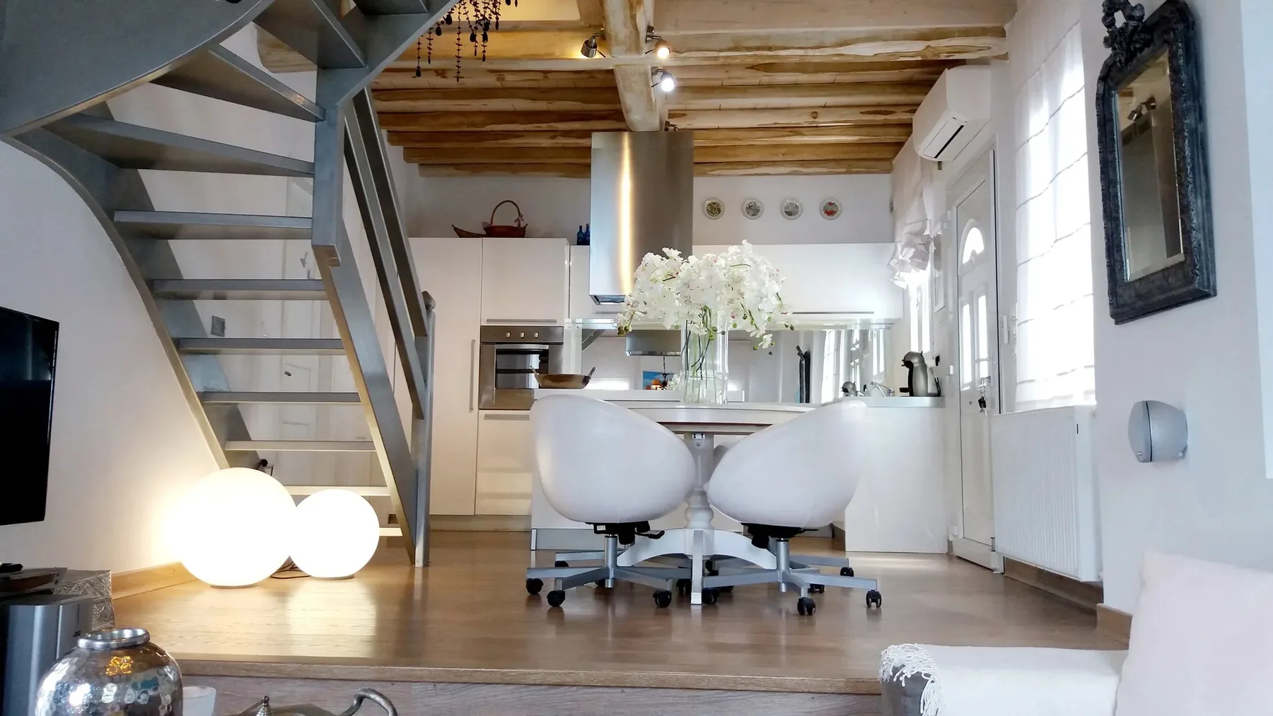 Una cocina y comedor de concepto abierto con una escalera y una mesa.