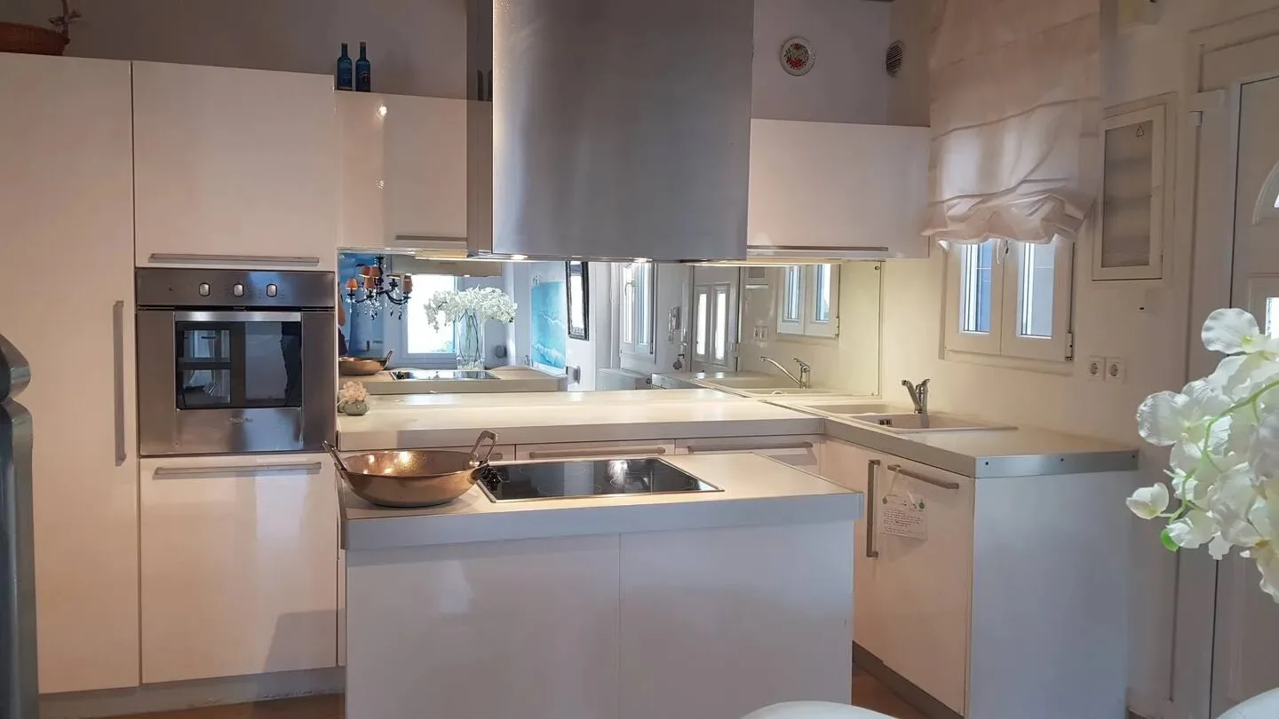 Una cocina luminosa con gabinetes blancos, una isla central y un horno empotrado.
