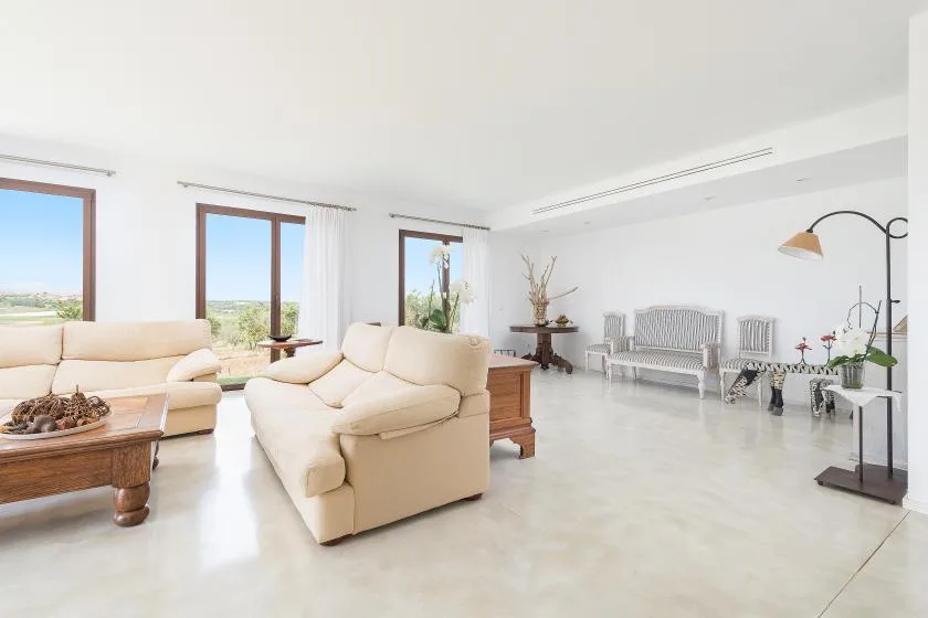 Una sala luminosa con asientos color crema y grandes ventanas con vistas al paisaje.