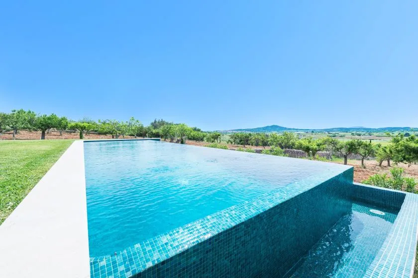 Una piscina al aire libre tiene vistas a campos verdes y colinas lejanas.