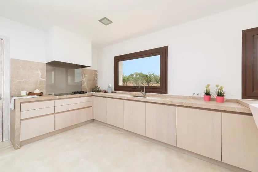 Una cocina luminosa con muebles claros y una ventana amplia sobre la encimera.