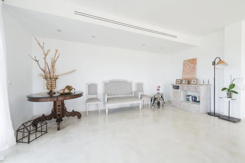 Una sala luminosa con asientos blancos, una mesa redonda y un mueble bajo.