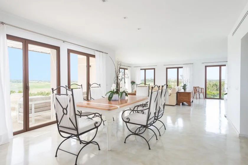 Un comedor luminoso tiene una mesa larga y grandes ventanas con vistas al paisaje.