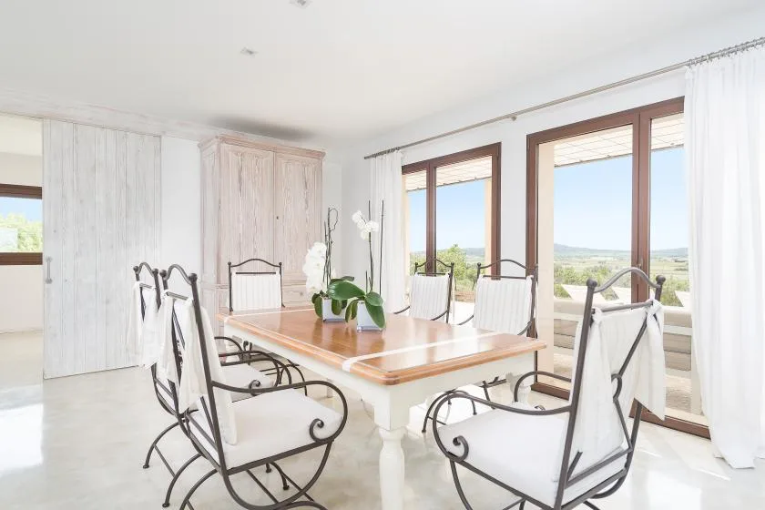 Un comedor luminoso con una mesa larga y grandes ventanas con vistas al paisaje.
