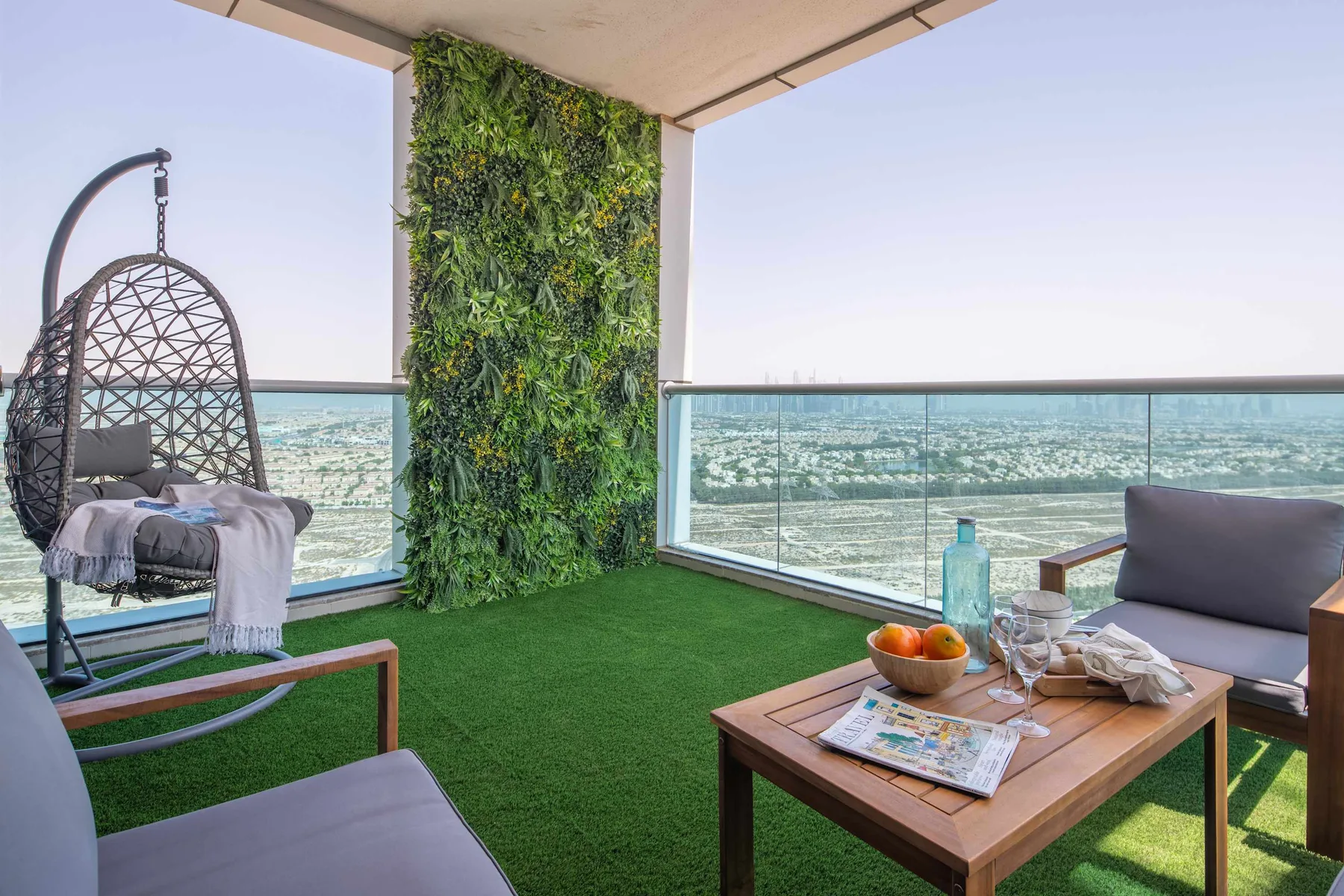A covered balcony seating area with a glass railing and a view over the water.