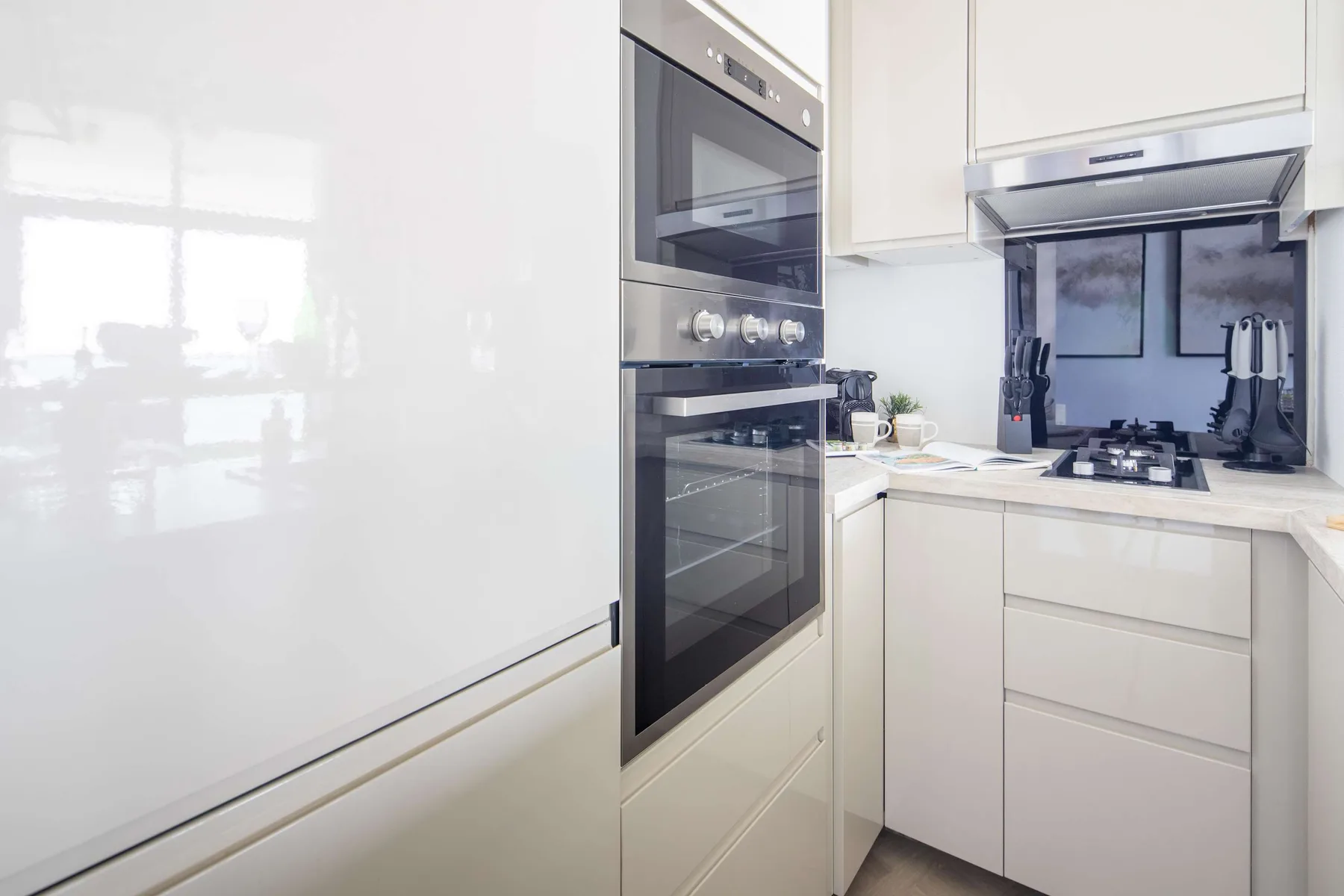 A bright modern kitchen with built-in appliances and a countertop cooktop.