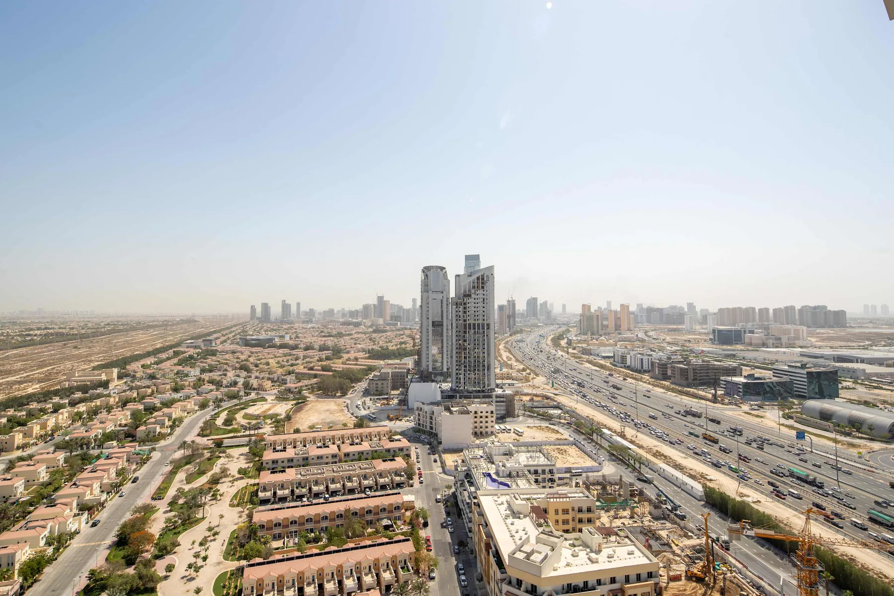 Aerial cityscape with a tall building, roads, and low-rise residential blocks.