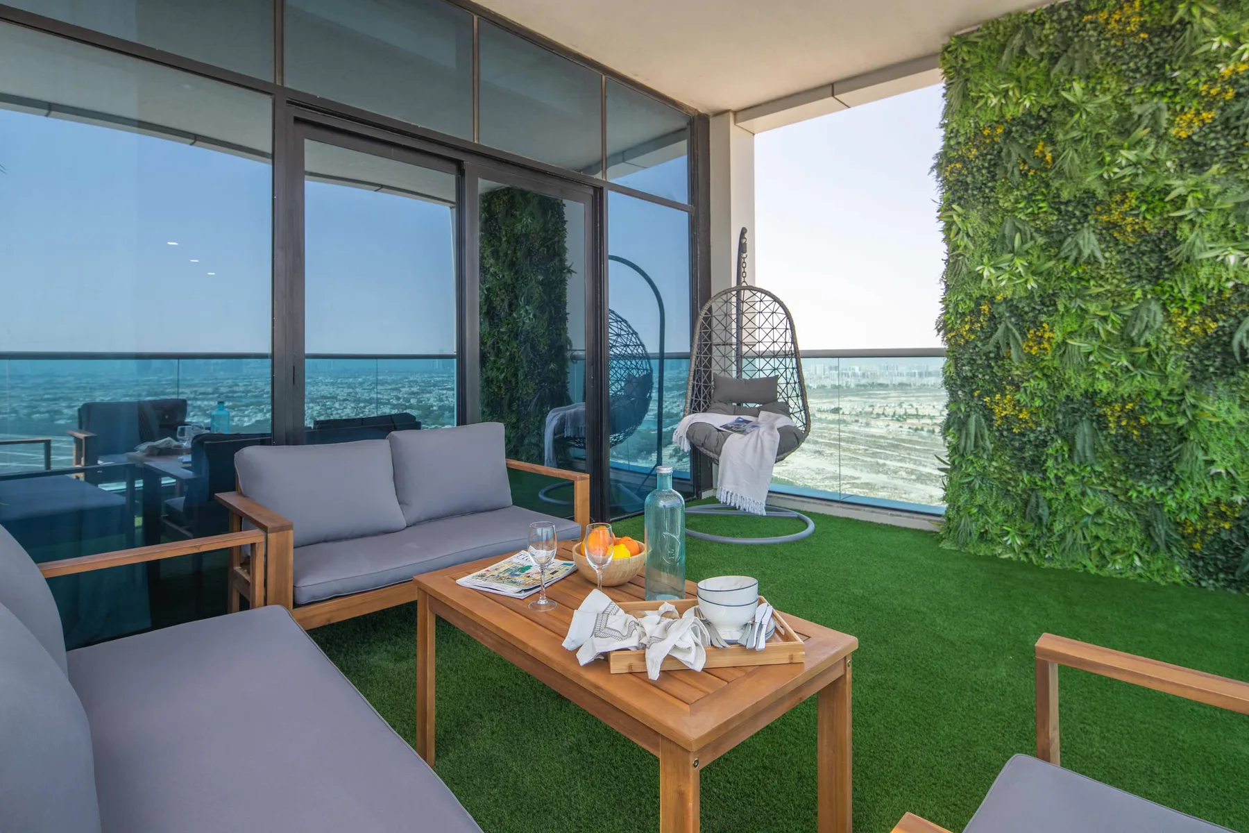 A furnished balcony with seating, a table, and a view of the sea.