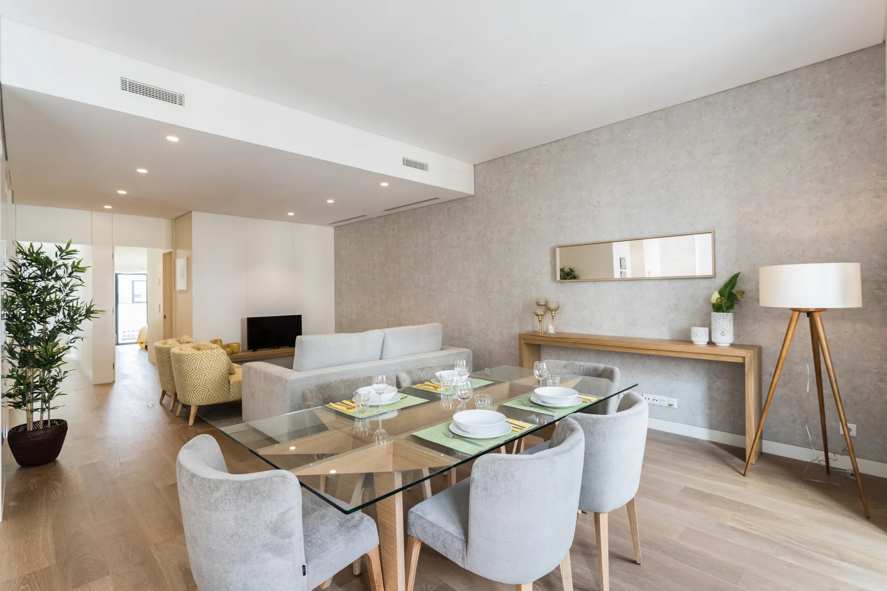 Sala de estar y comedor con una mesa de vidrio, asientos y un televisor.