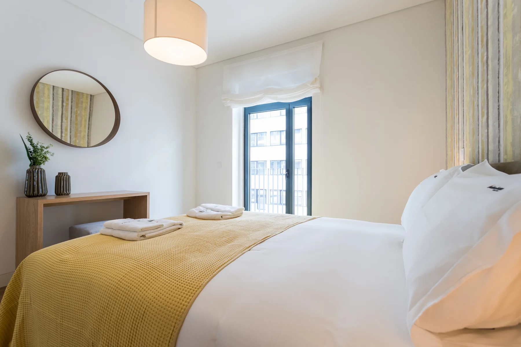 Un dormitorio luminoso con una cama tendida y una ventana.