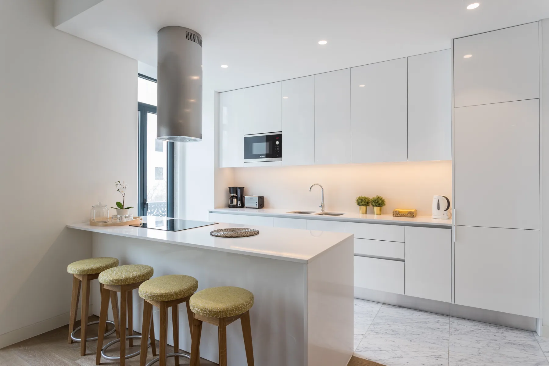 Una cocina moderna y luminosa con gabinetes blancos y una barra de desayuno.
