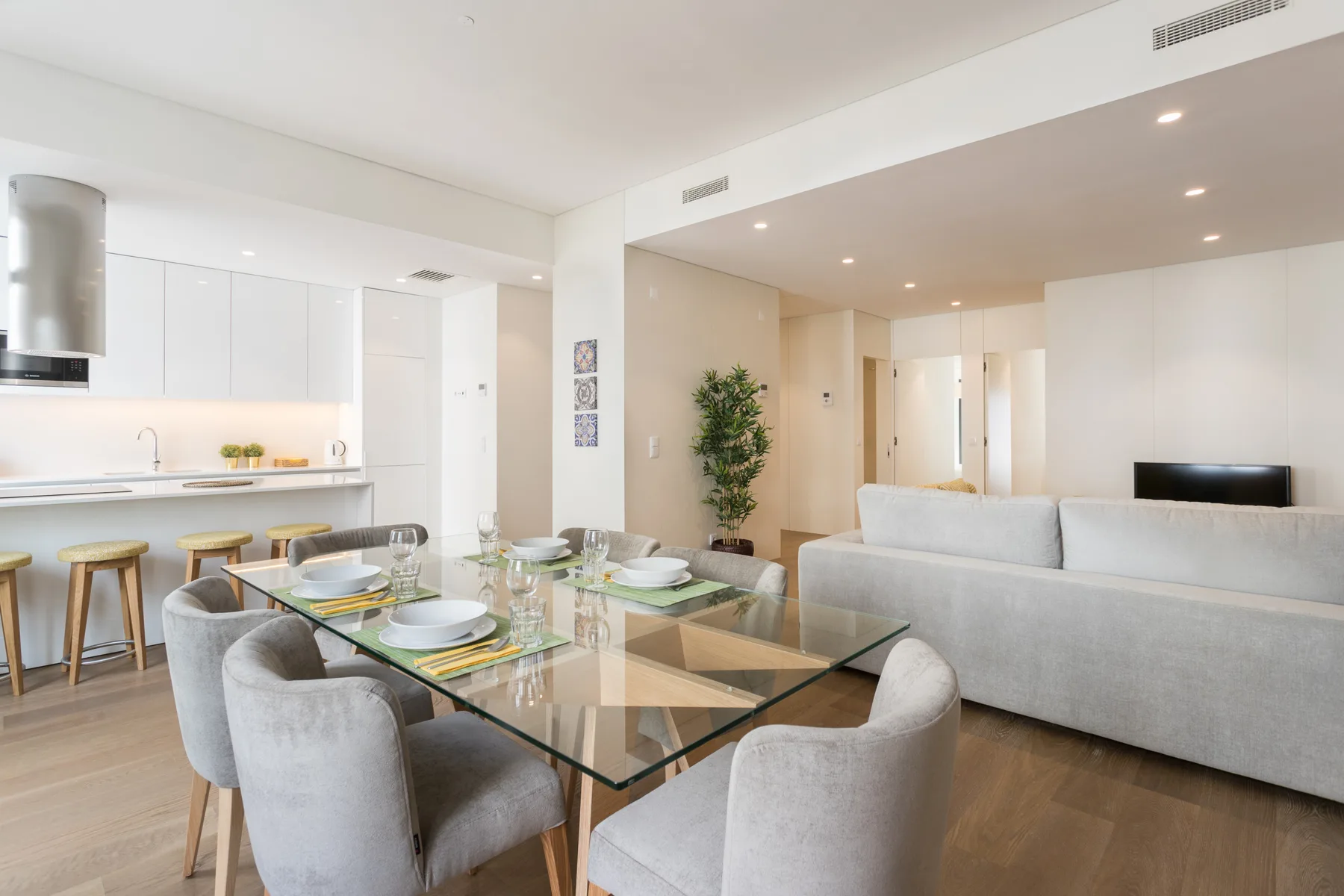 Una sala de estar y comedor diáfana con una mesa de vidrio y asientos.