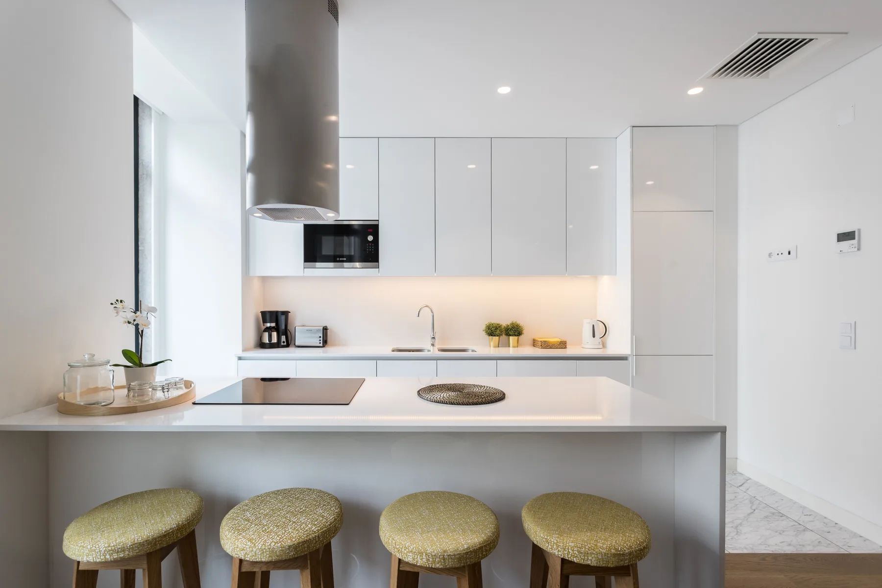 Una cocina moderna y luminosa con una isla larga y asientos de barra.