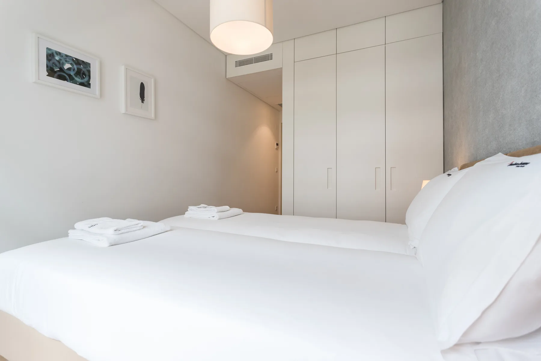 Un dormitorio luminoso con una cama bien hecha y armarios empotrados.