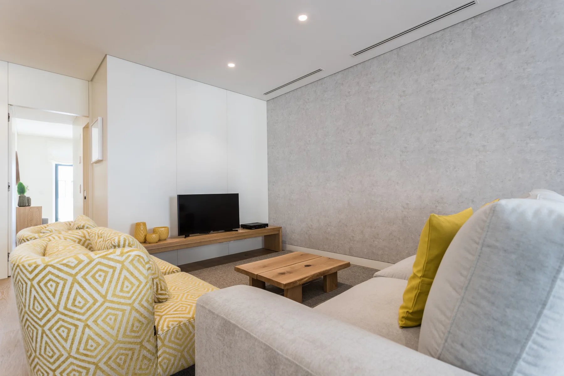 Una sala de estar moderna con asientos, un televisor y una mesa de centro de madera.