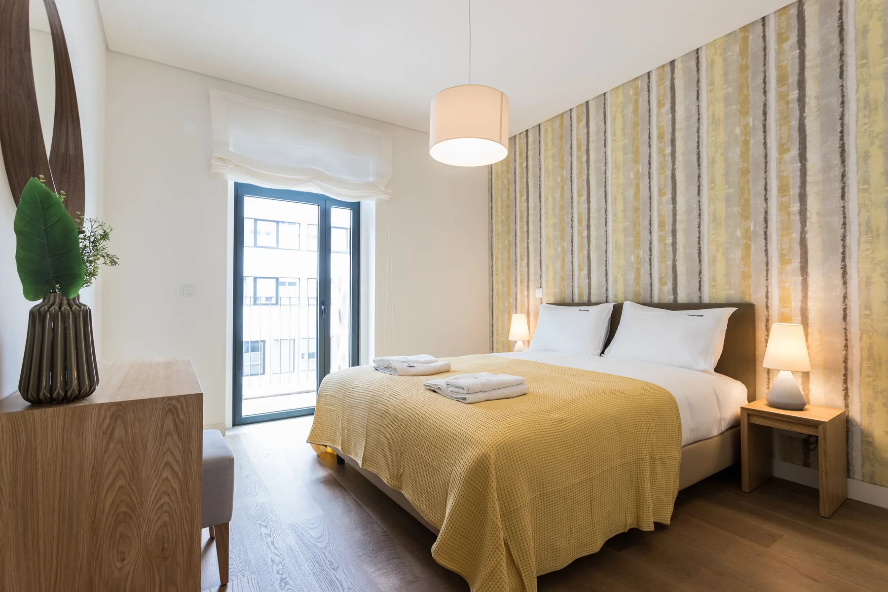 Un dormitorio con una cama doble, toallas dobladas y una ventana al lado.