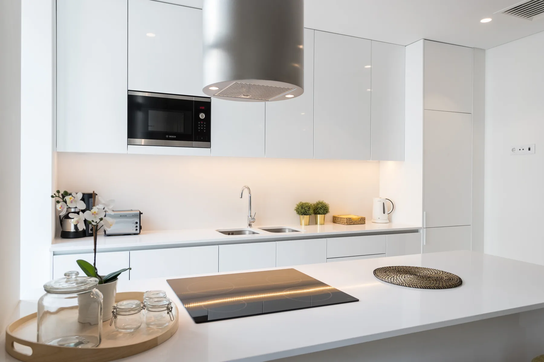 Una cocina moderna con gabinetes blancos y una placa de cocción sobre la encimera.