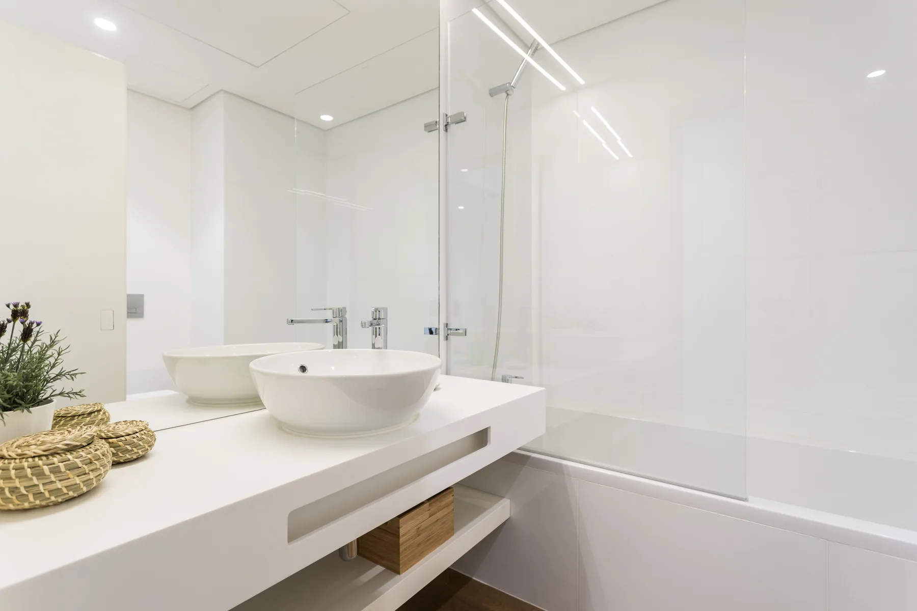 Baño luminoso con un amplio tocador, lavabo sobre encimera y bañera.