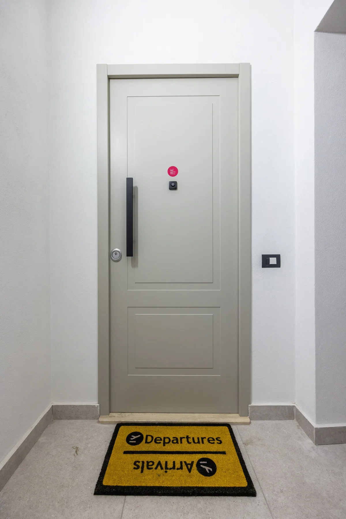 Una puerta interior cerrada está al final de un pasillo corto, con un tapete delante.
