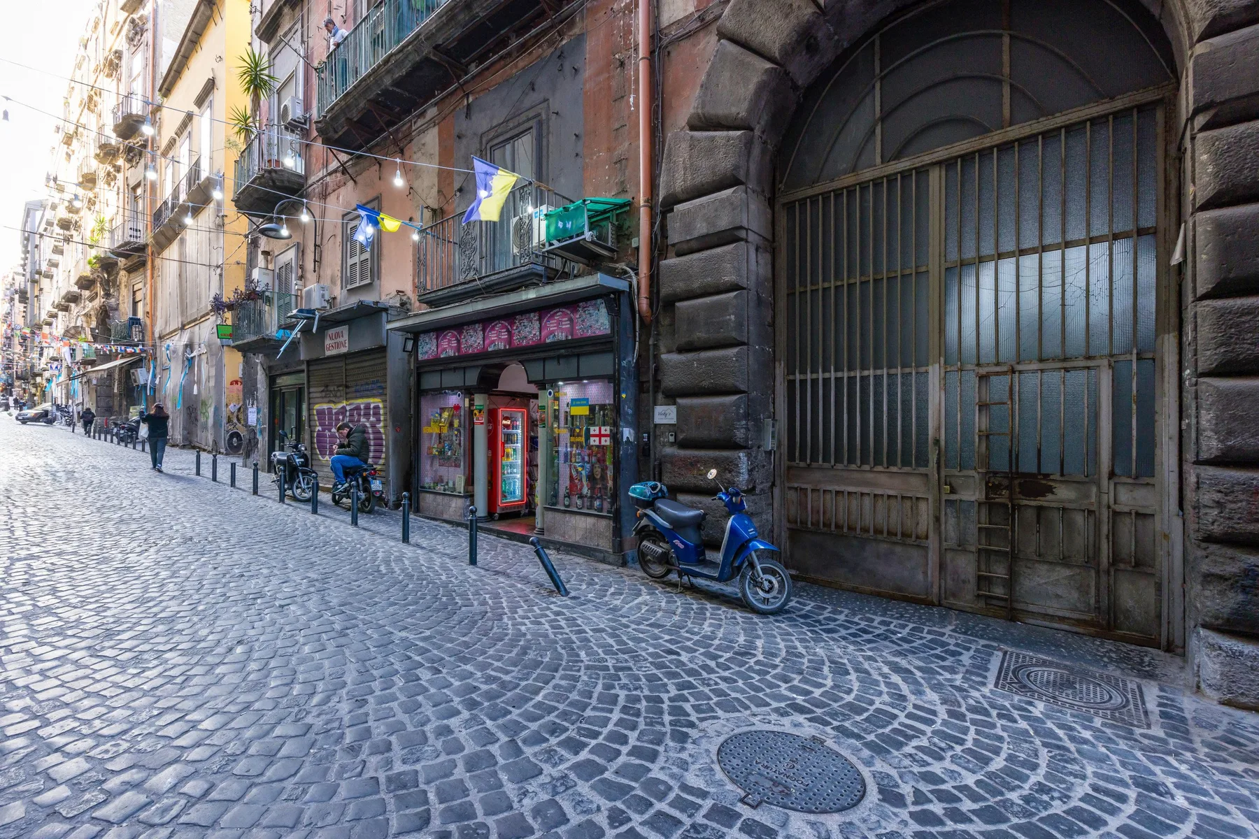 Una calle empedrada con tiendas y balcones.