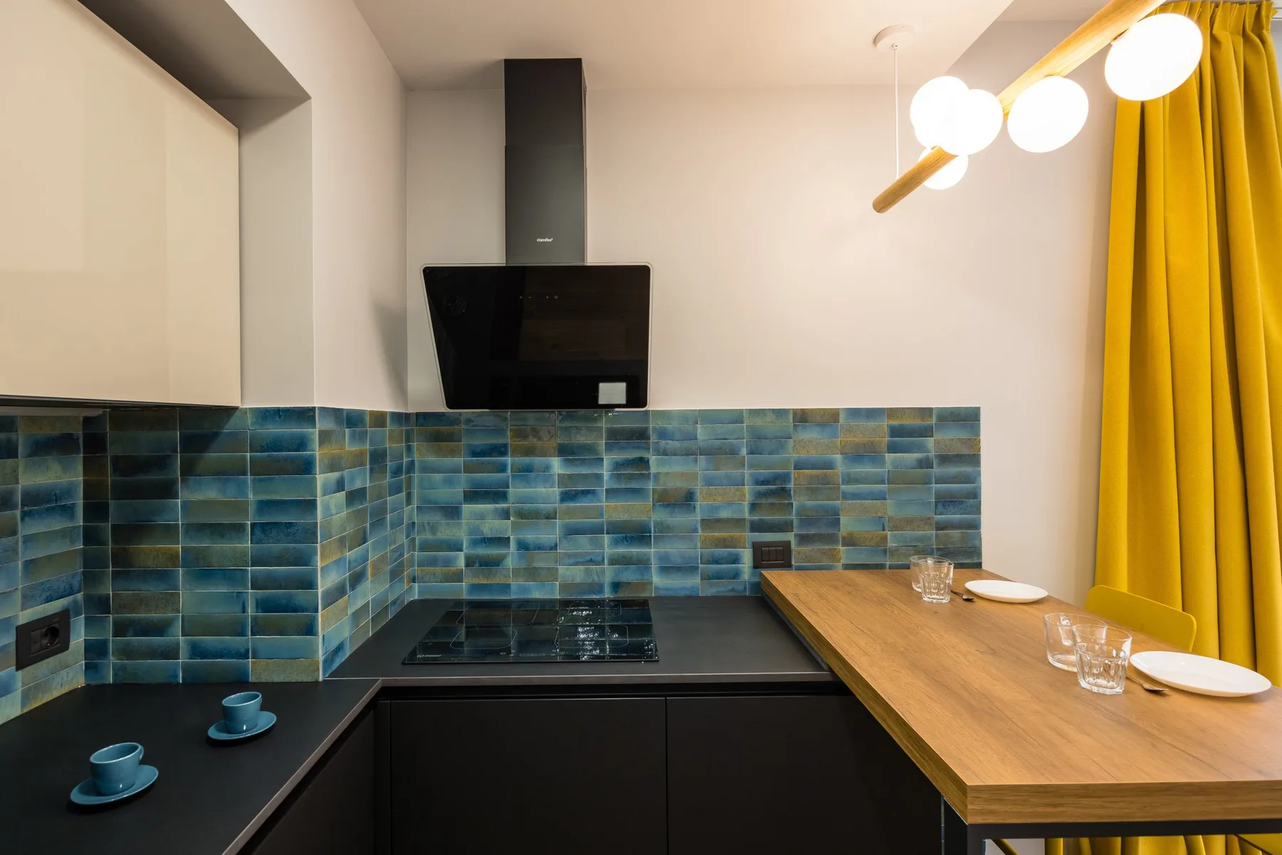 Una cocina compacta con salpicadero de azulejos y una barra de madera.