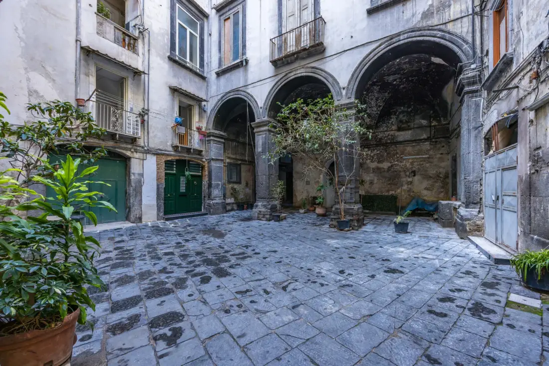 Un patio pavimentado está rodeado de edificios antiguos con arcos y balcones.