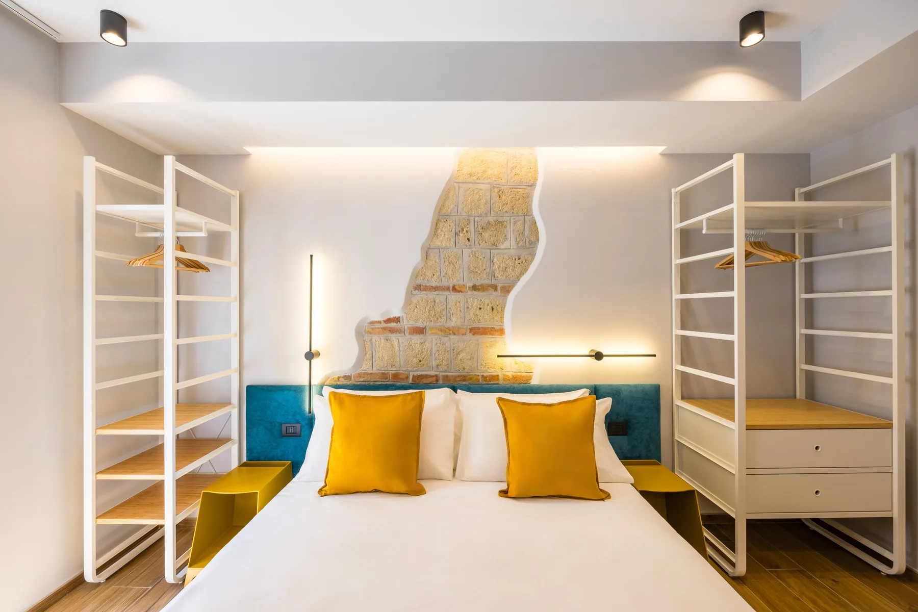 Un dormitorio con una cama, cojines dorados y estanterías a ambos lados.
