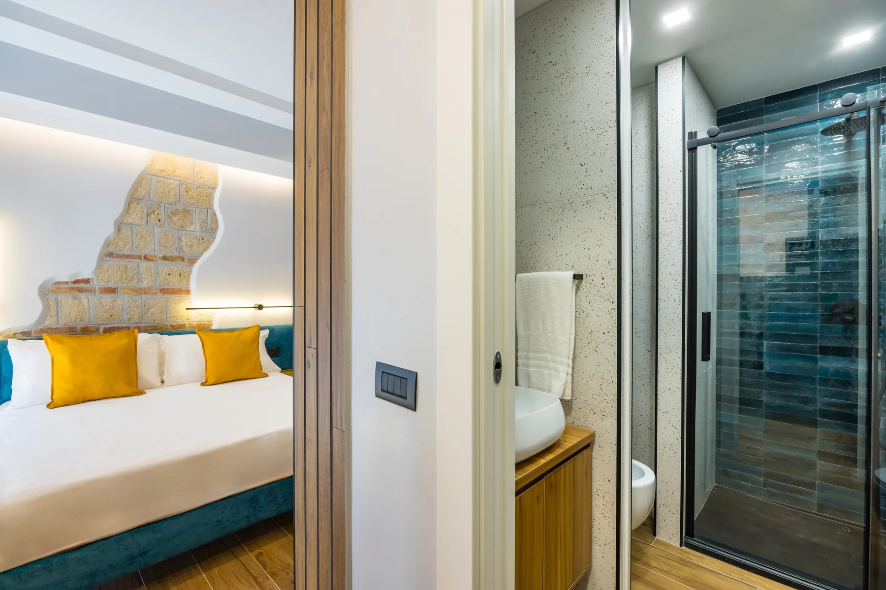Un dormitorio con una cama y cojines amarillos junto a un baño contiguo.