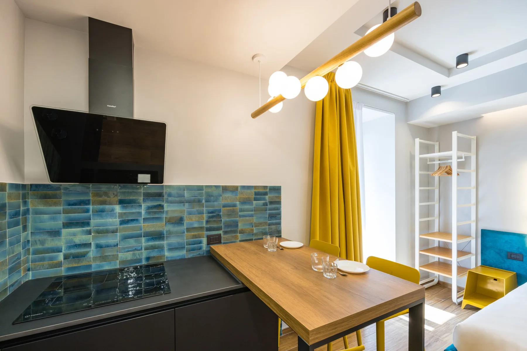 Cocina y comedor con una mesa de madera junto a un salpicadero de azulejos azules.
