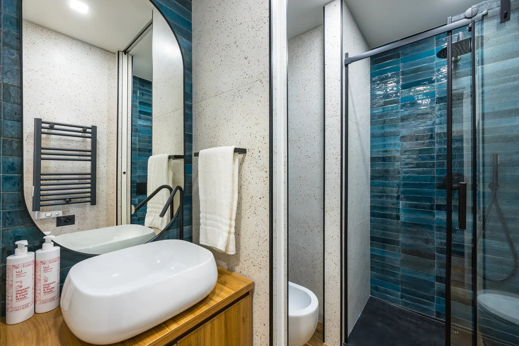 Un baño moderno con un lavabo blanco sobre encimera y una ducha con mampara de vidrio.